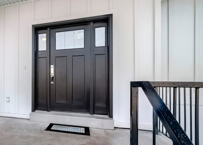 Panorama crop Home entrance with front porch and black front door against white panelled wall